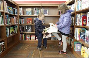 Students Jacob Phillips, 5, left, and his sister Shaina Phillips, 8, check out the books in the multimedia room/library.