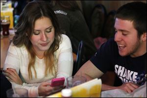 Ashley Langsdorf, 18, and a friend, Anthony Russo, 18, a freshman at Bowling Green State University, keep an eye on her Twitter feed during a party for her mother, Josie.