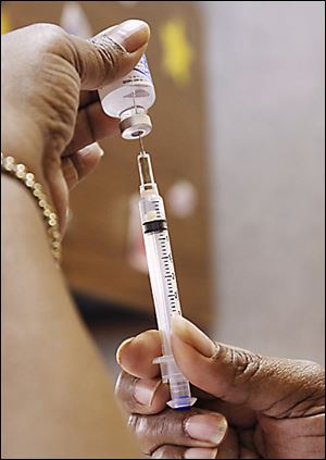 A public health nurse draws flu vaccine. Health officials urge residents to get vaccinated.