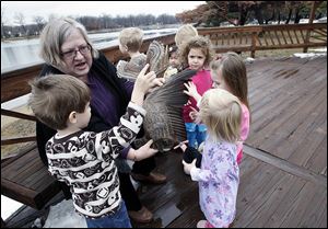 Maureen Schnell of Eco-Discovery shows youngsters a wing from a Canada Goose during the Nurturing Nature program at Olander Park in Sylvania on Friday.  Jamie Valasek, 3, left, holds a model of an owl while Jackie Jennewine, 2, right, touches the wing.  Nature topics vary week to week.