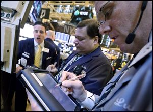 Traders work on the floor of the New York Stock Exchange. Stocks opened lower on Wall Street as concerns about the government’s finances intensified, offsetting a report that showed retail sales rose in December.