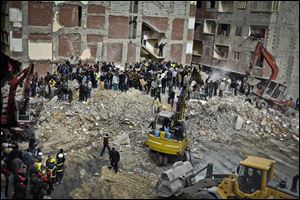 Egyptians stand in rubble after an eight story building collapsed in Alexandria, Egypt.