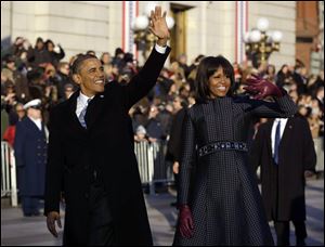 President Barack Obama and first lady Michelle Obama wave as they walk down Pennsylvania Avenue near the White House during the 57th Presidential Inauguration parade today.