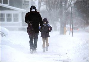 David Range walks his daughter Abigail Range, 10, to Perry Elementary in Erie, Pa. The freezing tempera-tures caused icy roads across much of the state.