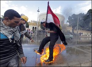 An Egyptian protester tries to escape from fire after he burned an anti-Mohammed Morsi banner in front of the presidential palace in Cairo, Egypt.