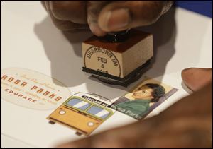 A postal service employee prepares to cancel the Rosa Parks' 100th birthday commemorative postage stamp at The Henry Ford museum in Dearborn, Mich.