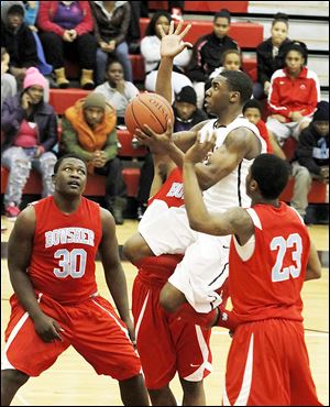 Rogers' Clemmye Owens drives past Bowsher's  Mark Washington (30) and Nate Allen during the second half. Owens scored 21 points for the 11-6 Rams.