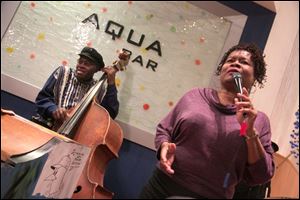 Clifford Murphy plays bass as Ramona Collins sings during Mr. Murphy's 81st birthday celebration at the Aqua Bar in the Grand Plaza hotel.