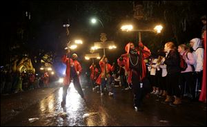 Flambeaus parade down St. Charles Avenue during the Krewe of Orpheus Mardi Gras parade in New Orleans, Monday.