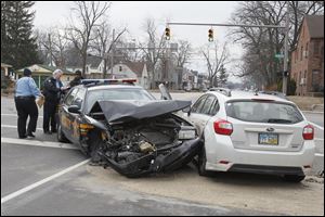 Toledo police officers speak to a Lucas County Sheriff's Deputy after a car crash on Douglas Road at Berdan in West Toledo early today.