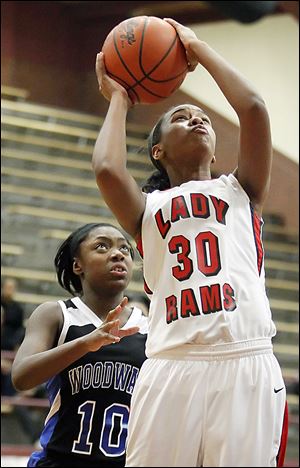 Rogers' Akienreh Johnson slips past Woodward's Asieonna Alfred on her way to the basket. Johnson and the rest of the Rams get a chance to defend their title on Saturday.