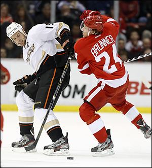 The Ducks' Ryan Getzlaf (15) is knocked off the puck by the Red Wings' Damien Brunner during the first period. 