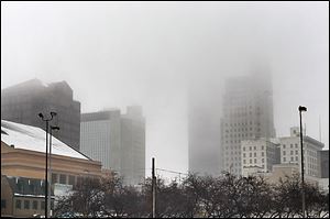 Fog envelops downtown Toledo. After snowfall overnight, temperatures hovered in the low to mid-30s much of the day.