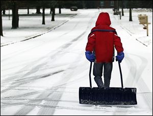 Toledoan Augustine Rancatore, 11, carries a big shovel as he walks to homes in South Toledo, selling his services of removing snow and ice from driveways and walks. Most schools were closed Friday.