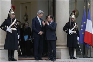 U.S. Secretary of State John Kerry, left, is accompanied by France's President Francois Hollande after their meeting at the Elysee Palace, in Paris, today.