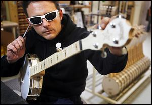 Tony Morbello uses a tuning fork instead of a digital tuner so he can hear the subtle tones while he strings, tunes, and gets the instruments ready to ship at the Deering Banjo Co. Prices for the instruments range from $499 to $30,000.