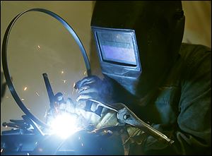 A welder works with the metal tension hoop at the Deering Banjo Co. Deering manufactures each banjo by hand. Greg Deering is the force behind the design and the machinery that builds them.