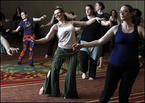 Barbara Rocci, second from left in pink sleeveless, and Kristy Windt, right, both of Ann Arbor, learn general belly dancing moves during a seminar at the Grand Plaza in Toledo.