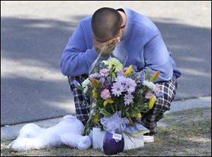 Jeremy Bush places flowers and a stuffed animal at a makeshift memorial today in front of a home where a sinkhole opened up underneath a bedroom late Thursday evening and swallowed his brother Jeffrey in Seffner, Fla.