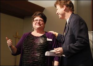 Toledoan Lisa Kronbach-Eisenbach, founder and director of Nightingales Harvest, left, gives an award to  Dr. Timothy C. Kasunic, right, who was Kim Mardini-Channer's oncologist.