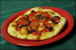 Homemade fresh tomato and sun-dried tomato  pizza is pictured.