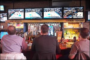 Walls of TV screens occupy patrons of Fricker's downtown who watched the first games of the NCAA basketball tournament. Businesses such as sports bars count on March Madness, which began Thursday, for a financial boost during the doldrums of late winter and early spring.