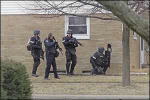 Members of a special response team made up of officers from Maumee, Sylvania, and Sylvania Township get into position Sunday near 1145 Kirk St. in Maumee.