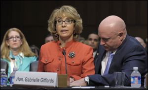 Former Arizona Rep. Gabrielle Giffords, who was seriously injured in the mass shooting that killed six people in Tucson, Ariz., in January 2011, is aided by her husband, Mark Kelly, as she speaks before the Senate Judiciary Committee hearing on gun violence on Capitol Hill in Washington on Jan. 30.