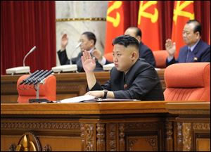 North Korean leader Kim Jong Un raises his hand with other officials to adopt a statement during a plenary meeting of the central committee of the ruling Workers' Party in Pyongyang, North Korea Sunday.