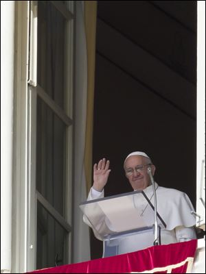 Pope Francis waves to the crowd after the Regina Coeli prayer from the window of his studio overlooking St. Peter's Square at the Vatican.