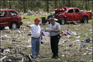 William White, left, speaks to his insurance agent Rick Anderson, from USAA, right, to asses the damage to his home and property that was destroyed by the tornado. White's truck, behind, was blown into their backyard.