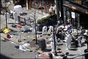 Investigators in haz-mat suits examine the scene of the second bombing on Boylston Street in Boston Tuesday, April 16, 2013 near the finish line of the 2013 Boston Marathon, a day after two blasts killed three and injured over 170 people.