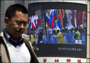 A Chinese man walks past a huge screen which reports Boston Marathon bombings that killed three and wounded more than 170 people, in Beijing, China today.