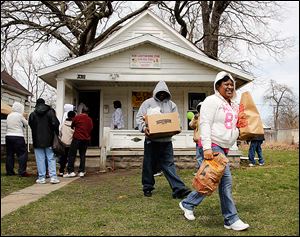 Carla Glover of Toledo carries food to her car after members of the New Light Shiningstar Food Pantry and the Circle of Friends minority health program handed out boxes of food to those in need Wednesday. The two agencies are drawing awareness to the services their organizations provide.