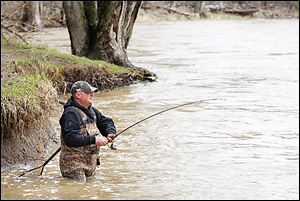 Greg Pauken of Maumee fishes close to the shoreline in the Maumee River at Side Cut Metropark. High water from recent rain adds a challenge to walleye fishing.