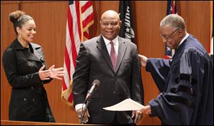 Phil Copeland is applauded by his daughter Sarah Copeland, after being sworn in as Lucas County recorder by Toledo Municipal Court Judge C. Allen McConnell, right, at One Government Center in Toledo, Friday, January 4, 2013.