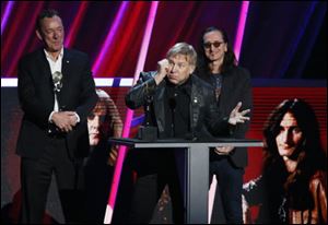 Alex Lifeson, center, Neil Peart, left, and Geddy Lee, right, of Rush accept their band's induction into the Rock and Roll Hall of Fame.