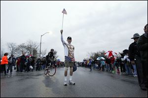 Tom Falvey waves a flag while runners get ready to start the 5k and half marathon during the Medical Mutual Glass City Marathon.