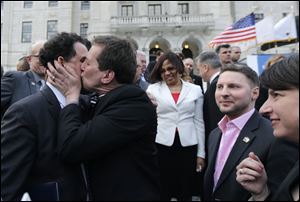 Rhode Island House Speaker Gordon Fox, left, is kissed by R.I. Rep. Frank Ferri, D-Warwick, after a gay marriage bill was signed into law outside the State House in Providence, R.I.