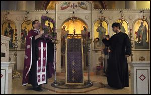 Fr. Aristotle Damaskos walks with an icon during Tuesday's Holy Week service at Holy Trinity Greek Orthodox Cathedral in Toledo, Ohio.  At right is seminarian David Mynihan.