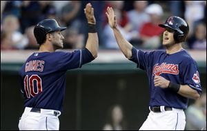 Cleveland Indians' Yan Gomes, left, and Drew Stubbs high-five after both scored on a triple by Jason Kipnis in the third inning.