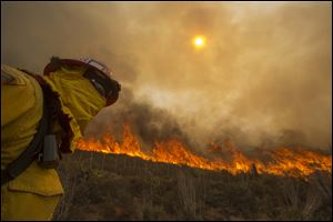 A firefighter keeps watch as the wildfire burns along a hillside in Point Mugu , Calif. 