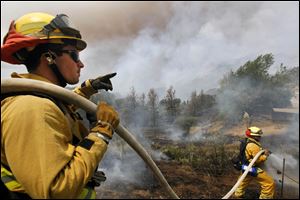 Firefighters from Riverside, Calif. work to extinguish a brush fire at Point Mugu, Calif. 