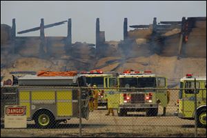 Fire trucks keep an eye on a burned structure at the Naval Base Ventura County at Point Mugu, Calif. 