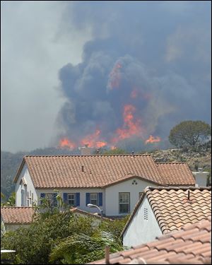 Fire burns behind homes during a wildfire that burned several thousand acres.