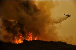 A firefighting helicopter makes a drop on a wildfire  in Thousand Oaks, Calif.