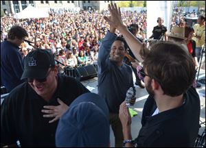 Actor Oscar Nunez, center, high-fives cast mate John Krasinski after singing on stage during 