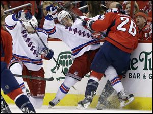 New York Rangers left wing Rick Nash, left, right wing Mats Zuccarello, center, and Washington Capitals center Matt Hendricks battle along the boards for control of the puck.