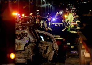 San Mateo County firefighters and California Highway Patrol investigate the scene of a limousine fire that killed five passengers on the westbound side of the San Mateo-Hayward Bridge in Foster City, Calif., Saturday, May 4, 2013. The Lincoln Town Car was packed with young women celebrating a girls' night out with a newlywed bride when it went up in flames. The driver and four women were able to escape. (AP Photo/Oakland Tribune-Bay Area News Group, Jane Tyska)