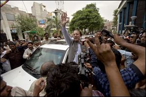 Former Prime Minister and leader of the Pakistan Muslim League, Nawaz Sharif, center, waves to his supporters as he leaves a polling station after casting his vote today in Lahore, Pakistan.